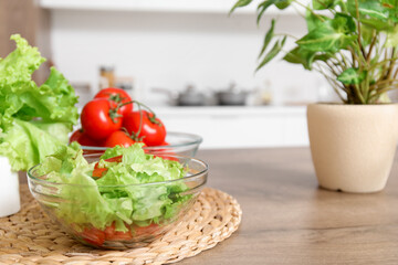 Wooden island table with fresh vegetables and houseplant in modern kitchen