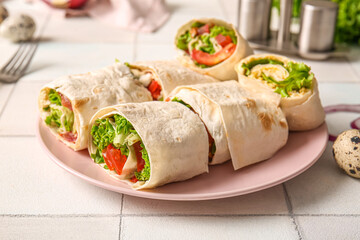 Plate of tasty lavash rolls with tomatoes, egg and greens on white tile background