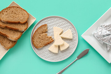 Plate with triangles of tasty processed cheese and bread pieces on turquoise background