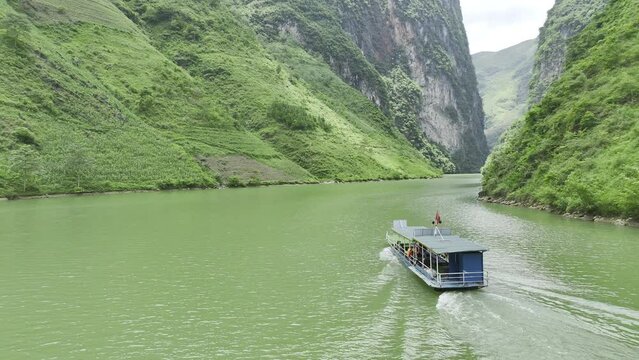 Aerial video of river boat tour for tourists on the Nho Quế River in Northern Vietnam with towering cliffs