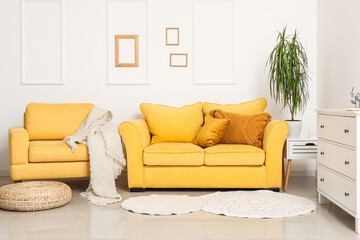 Interior of stylish living room with cozy yellow sofa, armchair and chest of drawers