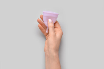Woman with menstrual cup on grey background
