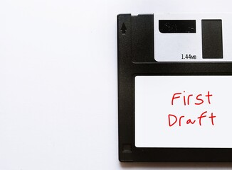 Vintage floppy disk with handwriting label FIRST DRAFT on copy space white background- concept of writing process, very first version of writing piece, script, book or novel