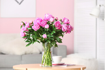 Vase of pink peonies on coffee table with couch in living room