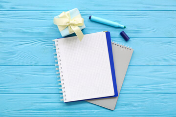Gift box with notebooks and marker on blue wooden background