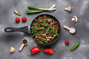 Frying pan with different vegetables on grunge background