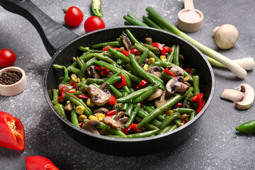 Frying pan with different vegetables on grunge background