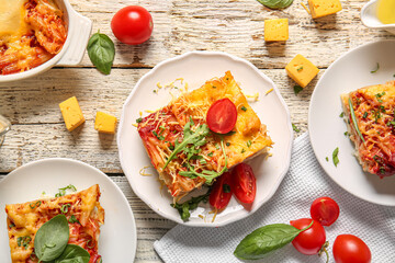 Plates and baking dish of pasta with tomato sauce on white wooden background