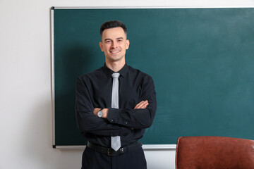 Male teacher near chalkboard in classroom