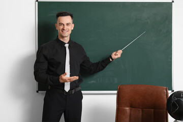 Male teacher with pointer near chalkboard in classroom