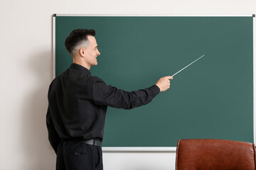 Male teacher with pointer near chalkboard in classroom