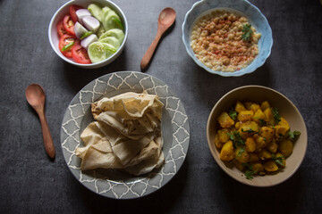 Popular Indian veg lunch rumali roti or Indian bread and alu jeera or potato masala served on a background. Top view