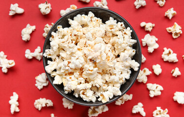 Bowl with tasty popcorn on red background