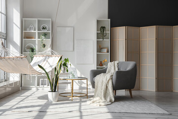 Interior of light living room with hammock, table and armchair