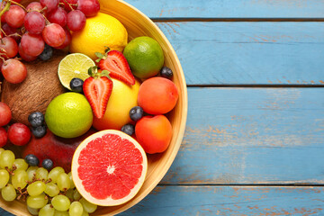 Bowl with different fresh fruits on blue wooden background