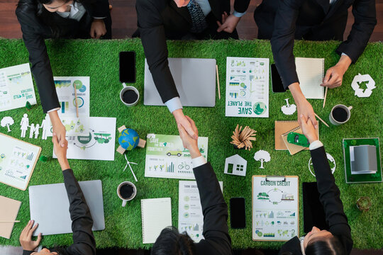 Top view panoramic banner of business people shake hand over meeting table on implementation of eco-regulation in corporate practice for environmental protection and sustainable future. Quaint