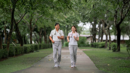 Young beautiful asian woman jogging with her father in park happily, with a smile. Asian woman jogging with her father for health care, park exercise, health care. concept health care life insurance.