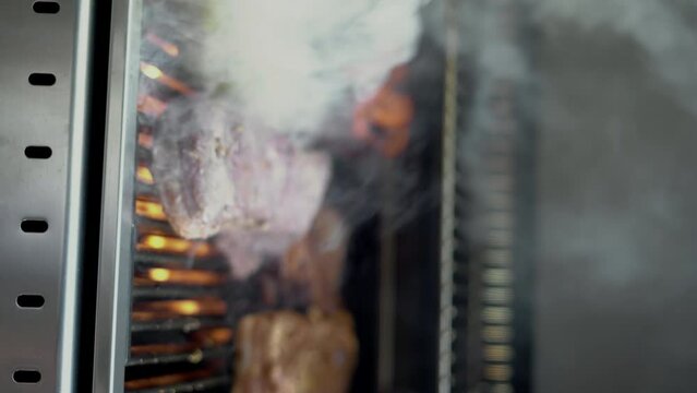 Pork and chicken steaks sizzling on the grill with smoke, barbecue meat summer concept