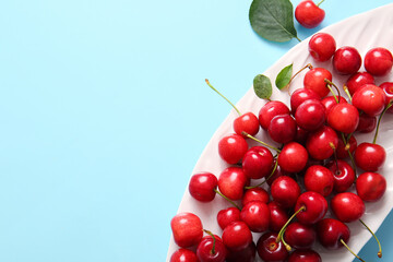 Plate sweet cherries on blue background