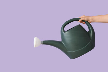 Gardener with watering can on lilac background