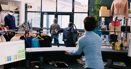 African american thief stealing trendy clothes, running from shopping centre. Asian bodyguard...