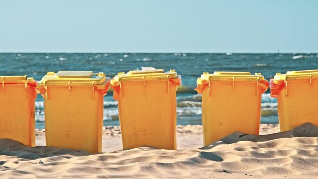 Row of Plastic Garbage Bins Deployed on Seashore Beach Sand