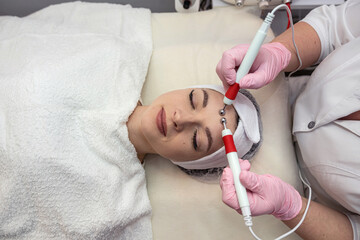 Young pretty woman receive microcurrent therapy procedure at beauty clinic