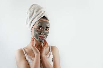 Beautiful girl with mud oy black clay facial mask isolated on white