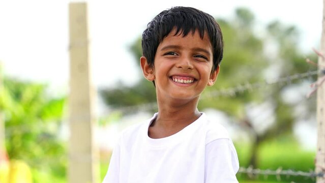 cute little boy with white t-shirt standing and looking into camera on nature light background