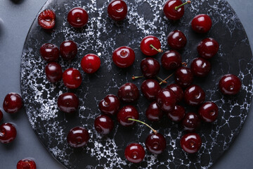 Board with sweet cherries on grey background
