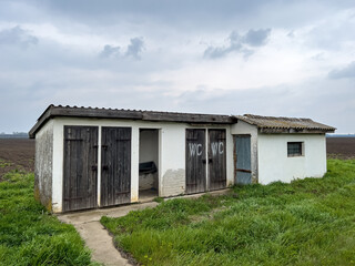 Fototapeta na wymiar Old outdoor toilet building in countryside landscape