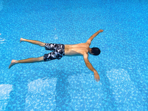 Drowned man floating in indoor swimming pool water, conceptual shot