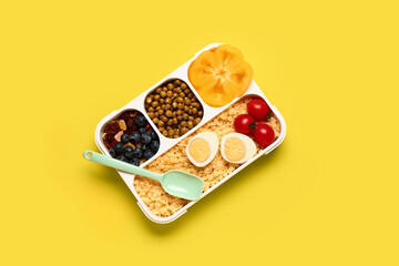Lunchbox with tasty food on yellow background