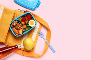 Backpack, bottle of lemonade and lunchbox with tasty food on pink background