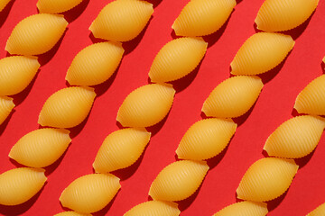 Uncooked conchiglioni pasta on red background