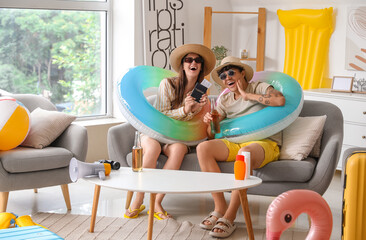 Young couple with beach accessories ready for summer vacation at home