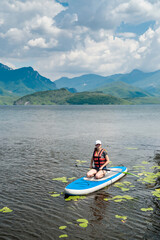 Fototapeta na wymiar young woman wear life vest paddle boarding on a lovely lake at summer hot day