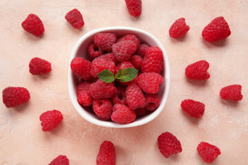 Bowl with fresh raspberry and mint on beige background, closeup