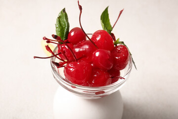Bowl of tasty maraschino cherries on light background