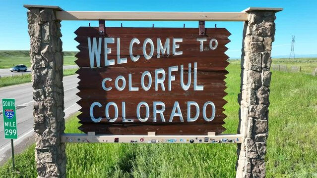 Welcome to Colorful Colorado road sign along highway. Aerial dolly forward establishing shot.