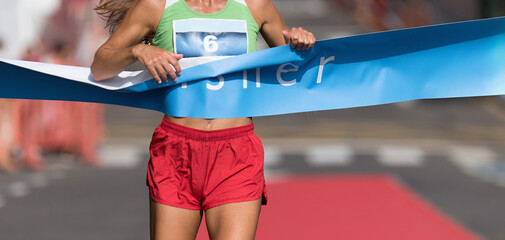 Woman running towards the finish line, female runner win the race outdoor in the city. Passes...