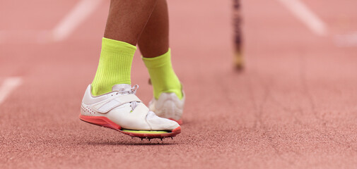 Fototapeta na wymiar Pole vaulter prepares for jump, detail of sports shoes spikes