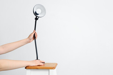 Woman with lamp on table against light background