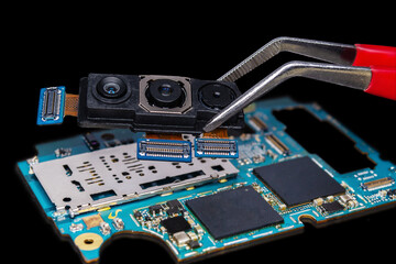 Close-up of a smartphone's triple camera held with tweezers