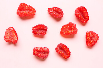 Pieces of fresh raspberries on pink background