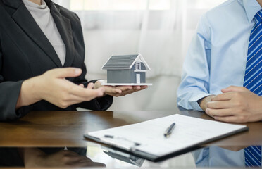 A real estate agent with House model is talking to clients about buying home insurance. Home insurance concept