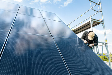 Technician working on a solar panel array on top of the roof of a house