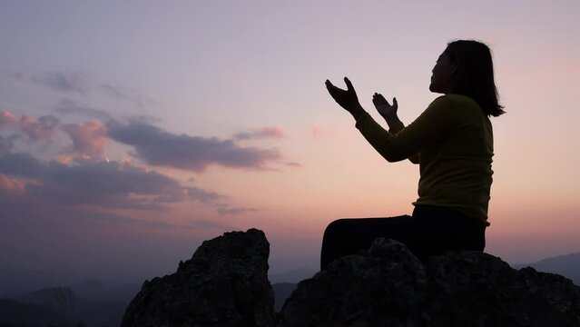 Silhouette of Christian woman praying worship at sunset. Christian Religion concept background. Hands  in prayer. worship god with religion concept.