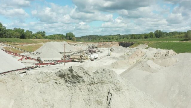 Drone Ascends Revealing Limestone Sand Quarry Behind Large Pile for Construction
