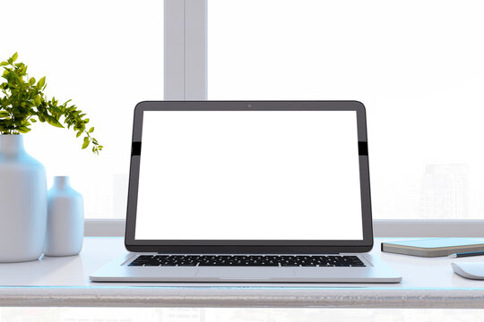 Close up of modern designer office desktop with white mock up laptop computer screen, decorative vase with plant, other objects and window with city view in the background. 3D Rendering.